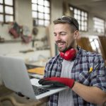 Ein lächelnder Handwerker, der einen B2B-Shop auf dem Computer anschaut