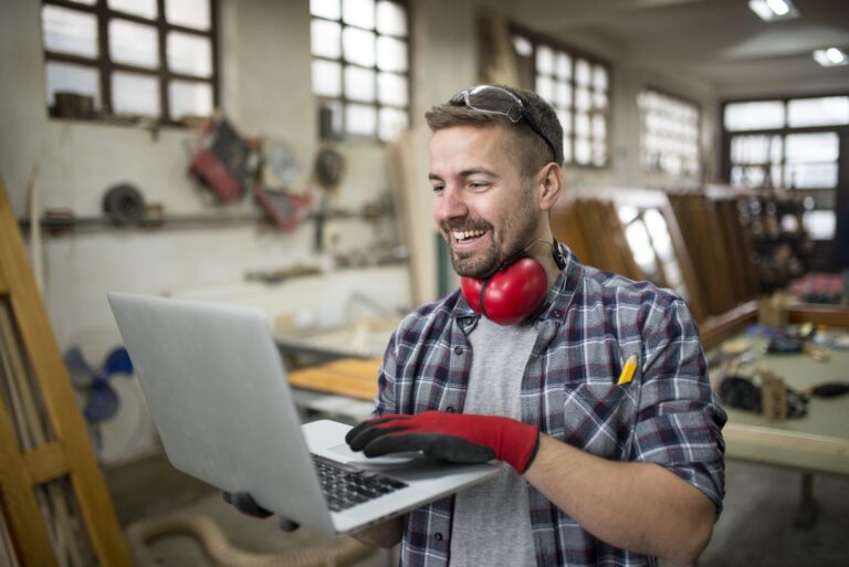 Ein lächelnder Handwerker, der einen B2B-Shop auf dem Computer anschaut
